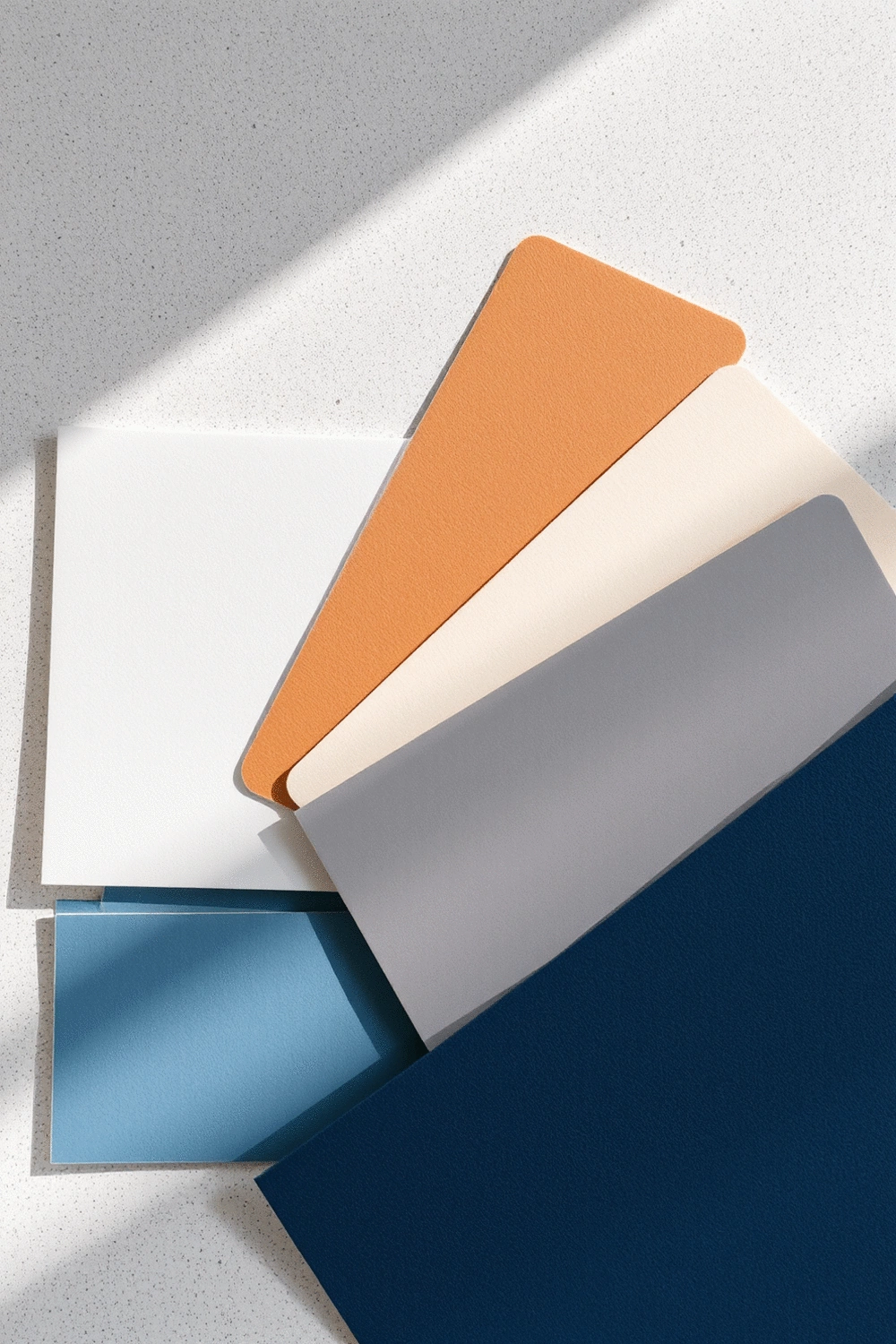 Color swatches displaying a palette of soft blues, warm grays, and muted earth tones, arranged neatly on a textured surface with gentle natural light.