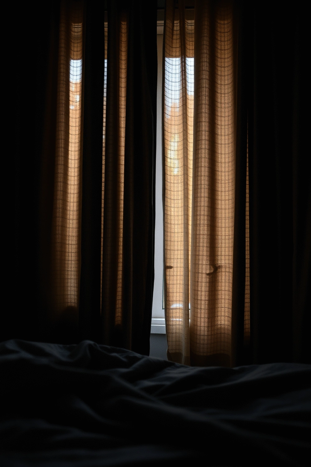 Close-up of a dark, heavy bedroom curtain blocking light from a window, creating a serene and dark sleep environment.