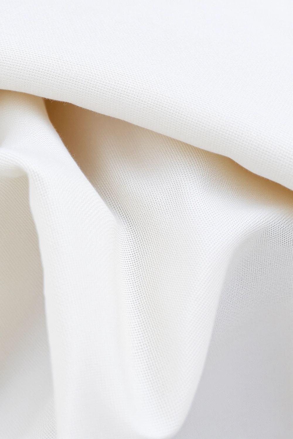 Close-up of neatly folded cotton, bamboo, and linen fabric swatches, showcasing their distinct textures and weaves. Natural light, soft shadows, clean background.